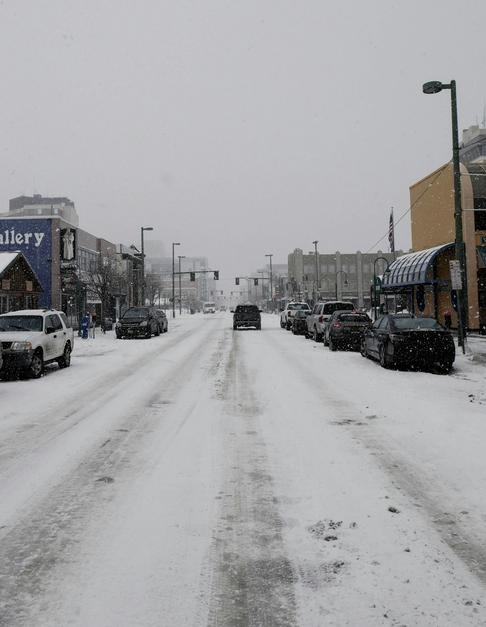 Snowy town street with parked cars
